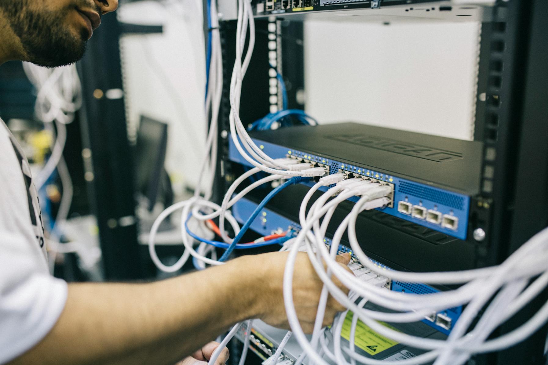 Symbolbild: Techniker arbeitet an Netzwerkanschlüssen in einem Serverschrank